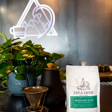 Cupla Coffee bag with pour-over setup and plant.